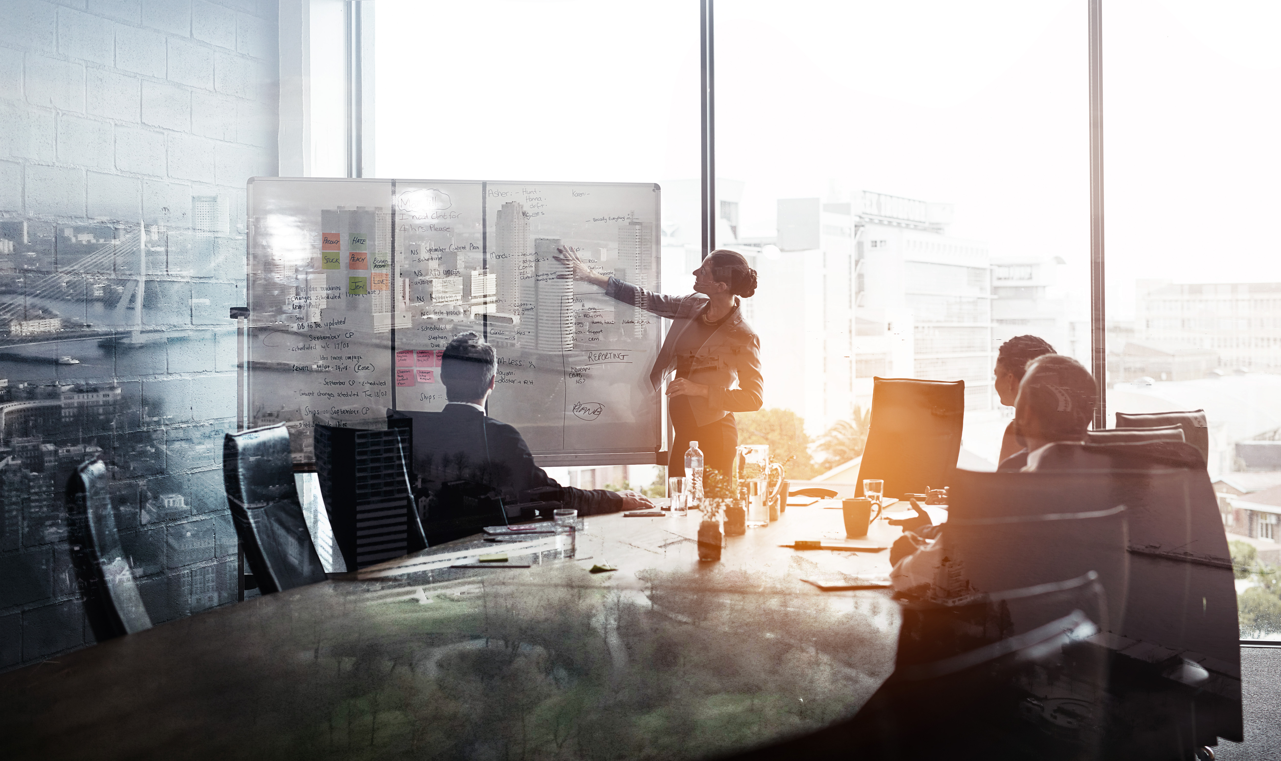 Multiple exposure shot of businesspeople in a meeting superimposed on a cityscape